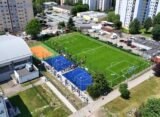 Kompleks boisk przy SP 54 w Giszowcu widziany z lotu ptaka — boisko piłkarskie z zieloną murawą, niebieskie boiska do streetballu i pomarańczowe boisko do siatkówki