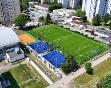Kompleks boisk przy SP 54 w Giszowcu widziany z lotu ptaka — boisko piłkarskie z zieloną murawą, niebieskie boiska do streetballu i pomarańczowe boisko do siatkówki