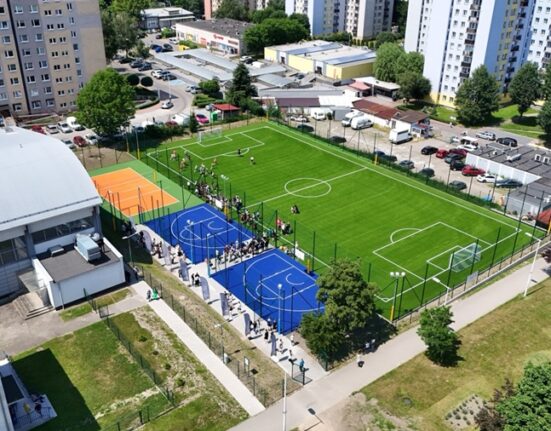 Kompleks boisk przy SP 54 w Giszowcu widziany z lotu ptaka — boisko piłkarskie z zieloną murawą, niebieskie boiska do streetballu i pomarańczowe boisko do siatkówki