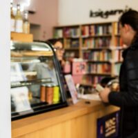 Wnętrze lokalu kulturalnego działającego w ramach programu Lokal na kulturę w Katowicach — księgarnia z kawiarnią, klientka przy ladzie