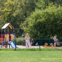Istniejący plac zabaw dla dzieci w Dolinie Trzech Stawów w Katowicach — zestaw ze zjeżdżalnią i kiwaki, w tle zieleń parkowa